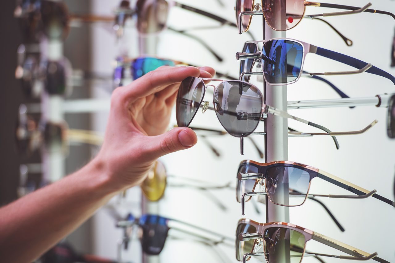 Hand nimmt eine Pilotensonnenbrille aus einem Brillenständer